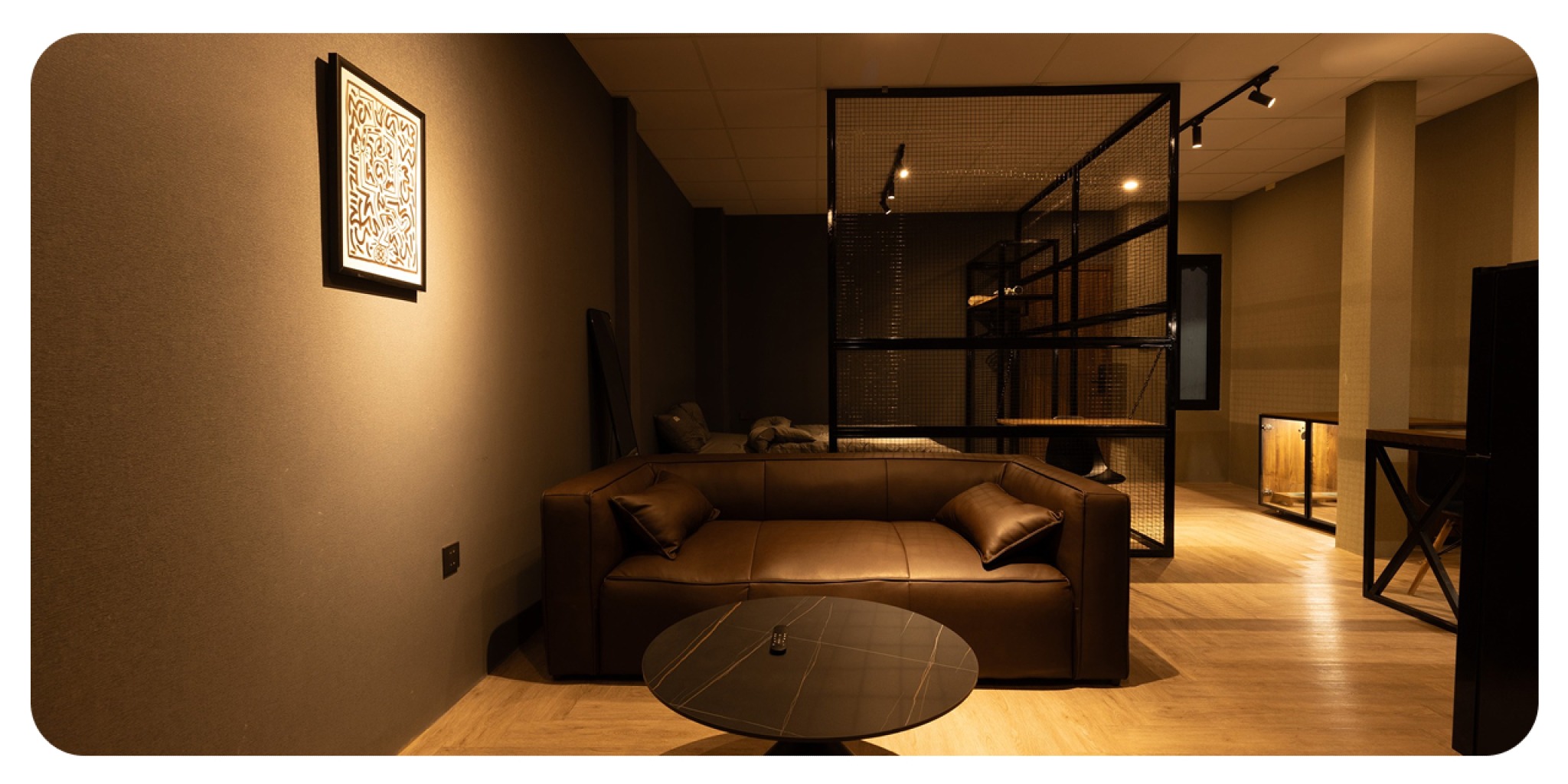 hu vực sofa da n&acirc;u, b&agrave;n tr&agrave; đ&aacute; v&agrave; v&aacute;ch ngăn lưới th&eacute;p trong ph&ograve;ng kh&aacute;ch Midas Home, thể hiện phong c&aacute;ch decor tinh tế v&agrave; sang trọng